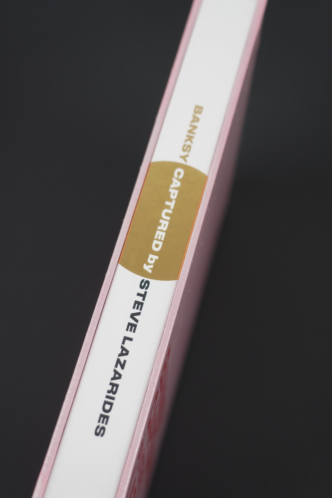 Close-up of the spine on Banksy Captured Volume 2, showcasing its elegant gold foil and slipcase texture.