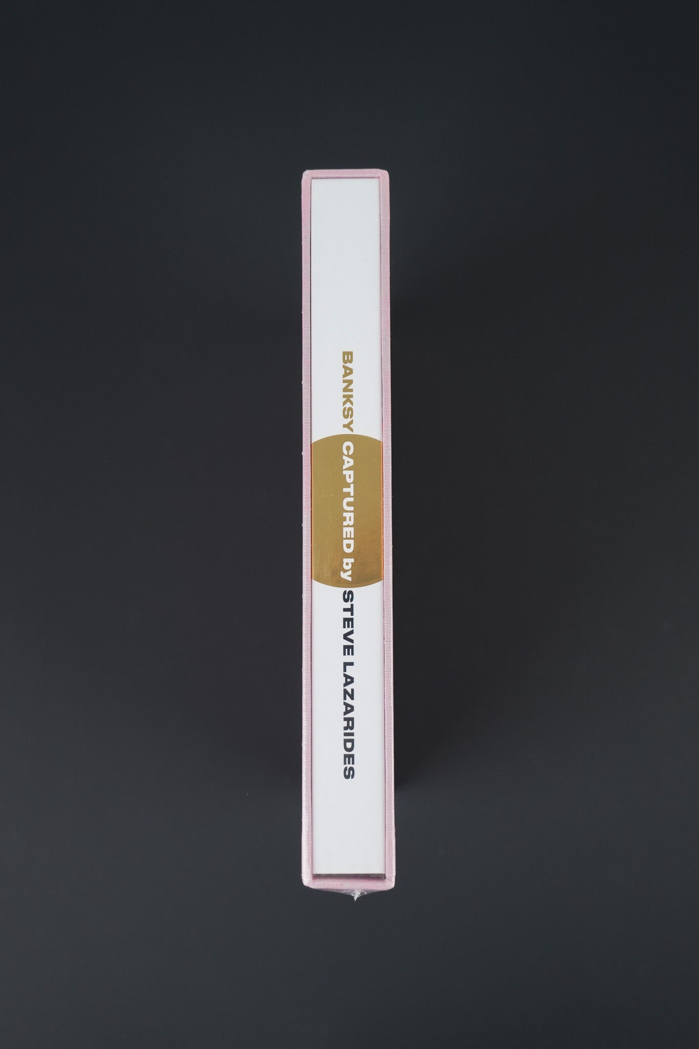 Close-up of the spine on Banksy Captured Volume 2, showcasing its elegant gold foil and slipcase texture.