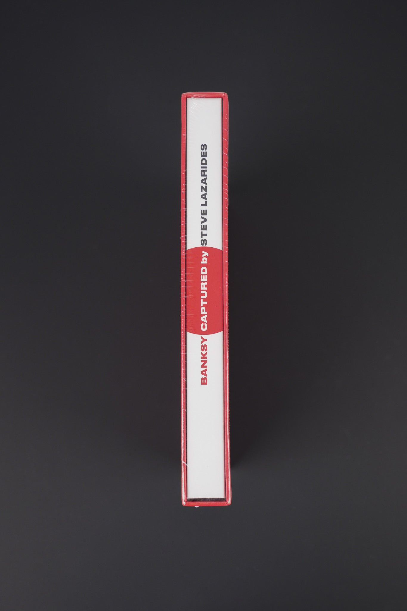 Close-up of the spine of the sealed Banksy Captured red edition, emphasizing its bold and elegant appearance.