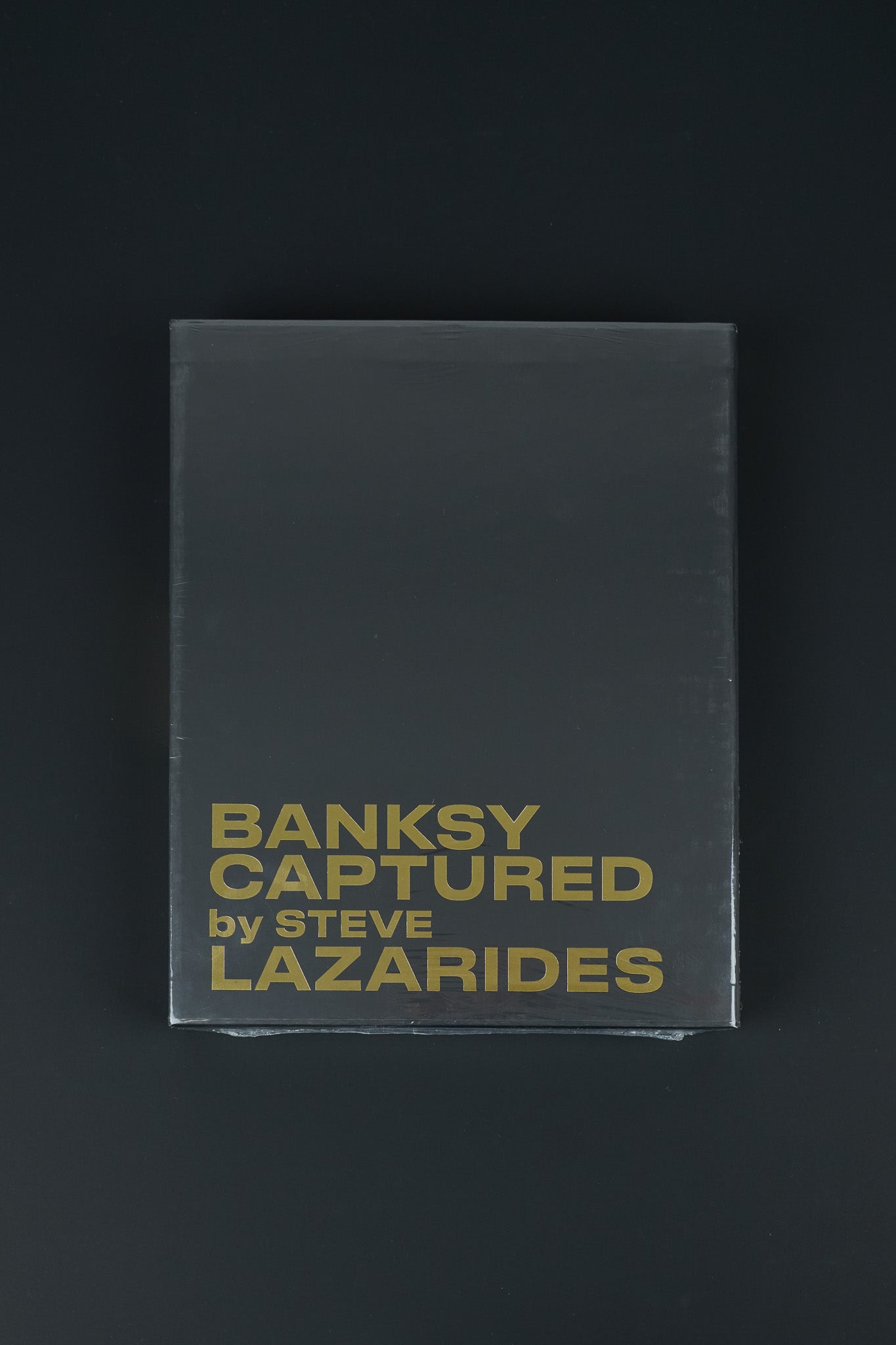 Black slipcase of the Banksy Captured book with gold foil details, a must-have for Banksy collectors.