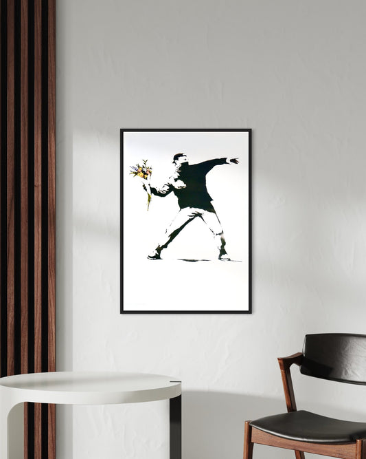 Framed 'Flower Thrower' print by Banksy displayed on a wall, adding a striking focal point to the room.