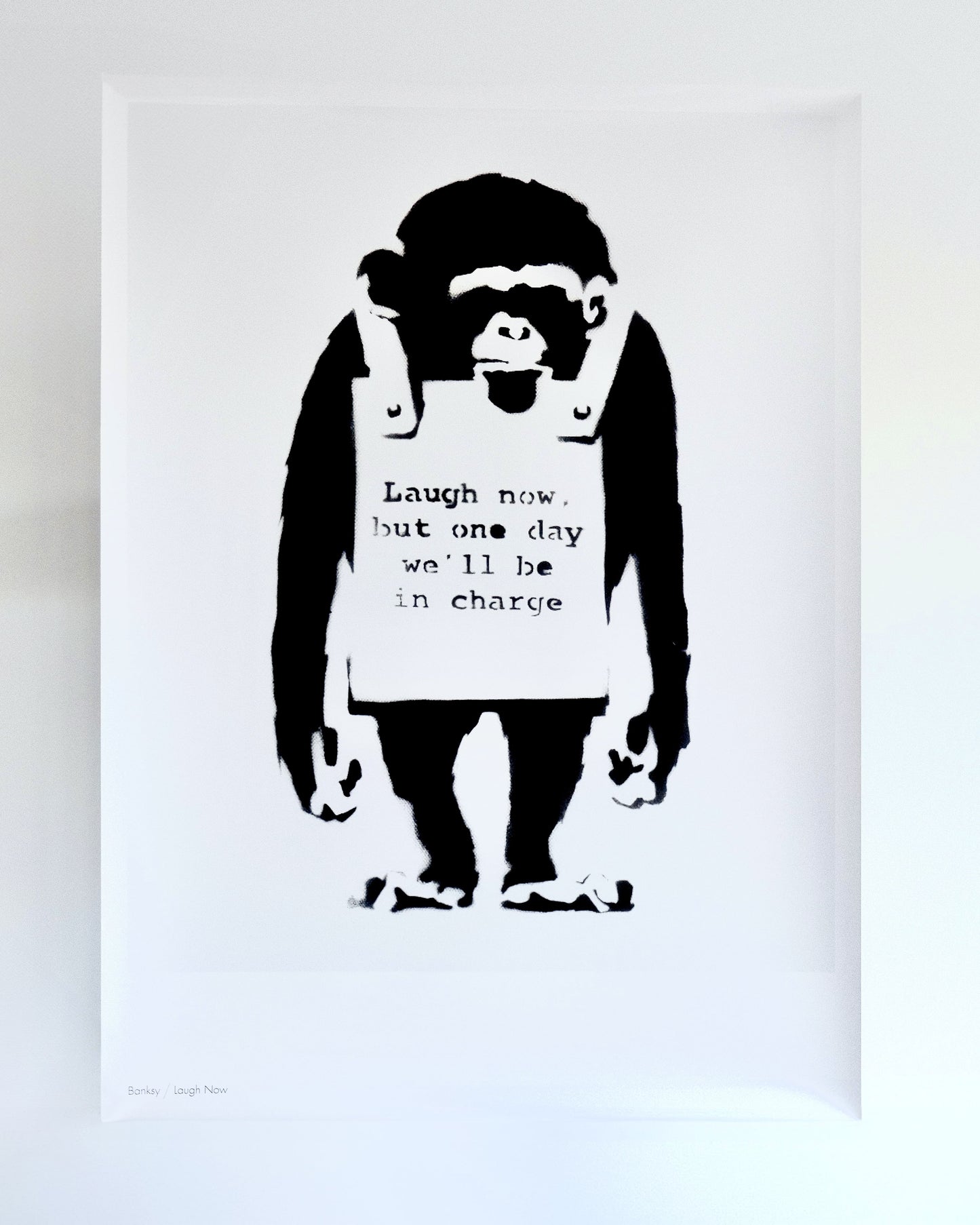 Detailed view of Banksy's 'Laugh Now' print, showcasing the satirical monkey and thought-provoking text.