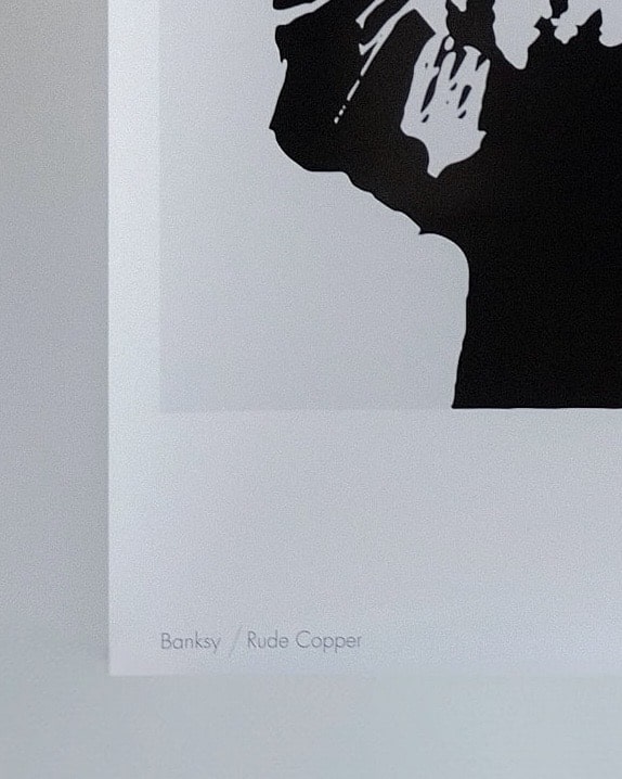 Close-up look at the print of "Rude Copper” by Banksy where written Banksy / Rude Copper.