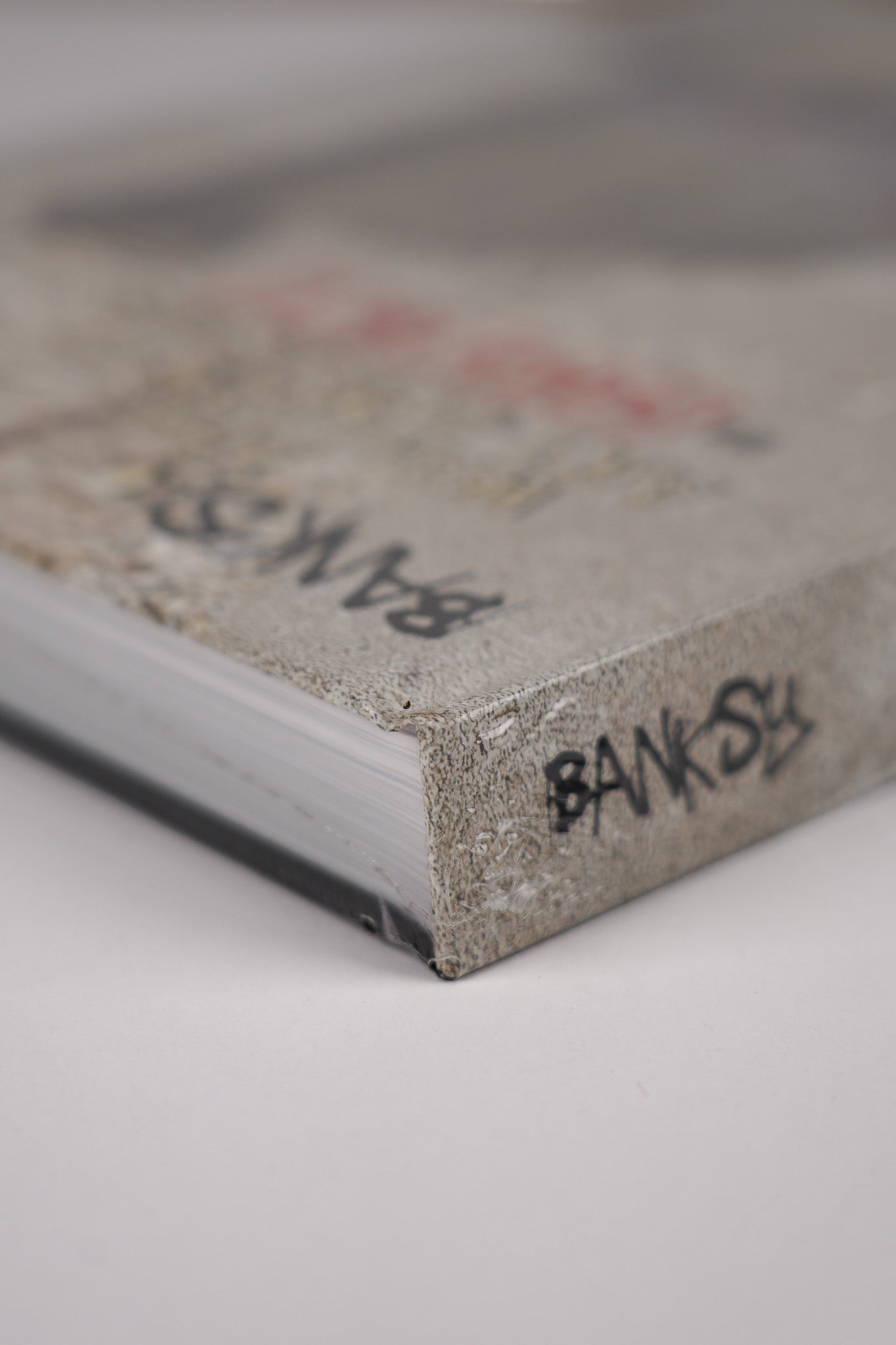 Top left corner of the front cover of "Banksy: The Walled Off Art Editions Are Sold Out" with fine detail of the book's edge.