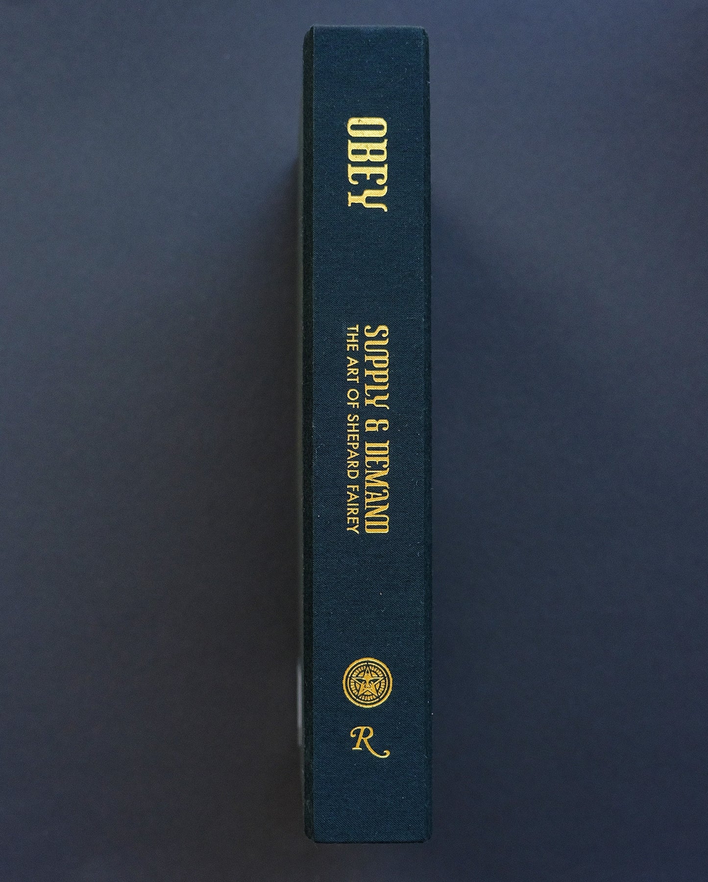 Spine of 'Obey: Supply & Demand - The 20 Year Edition' with the title and author Obey in bold lettering.